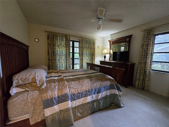 bedroom with multiple windows, carpet floors, a ceiling fan, and a textured ceiling