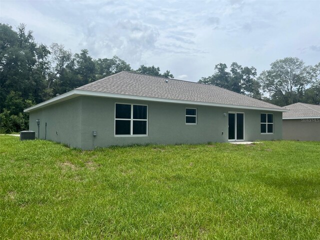 4105 SE 138th Pl, Summerfield, FL 34491 - rear view of house with stucco siding, a shingled roof, a lawn, and central AC