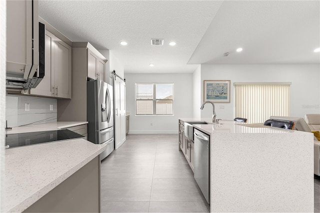 10291 SE 67th Ter, Belleview, FL 34420 - kitchen with stainless steel appliances, recessed lighting, gray cabinetry, light stone counters, and an island with sink