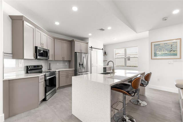 10291 SE 67th Ter, Belleview, FL 34420 - kitchen with stainless steel appliances, gray cabinetry, a sink, a kitchen bar, and recessed lighting