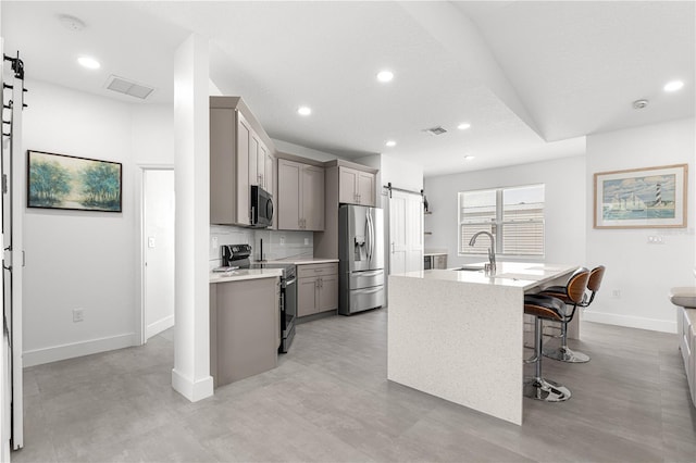 10291 SE 67th Ter, Belleview, FL 34420 - kitchen with stainless steel appliances, a barn door, gray cabinetry, light countertops, and a center island with sink