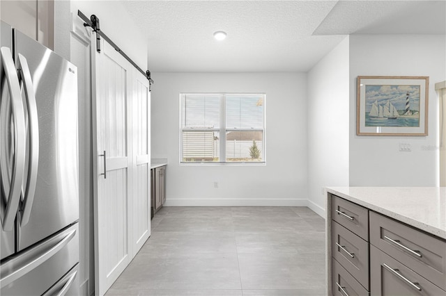 10291 SE 67th Ter, Belleview, FL 34420 - kitchen featuring freestanding refrigerator, a barn door, gray cabinets, light stone countertops, and baseboards