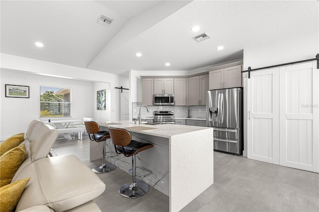 10291 SE 67th Ter, Belleview, FL 34420 - kitchen with a barn door, appliances with stainless steel finishes, gray cabinets, open floor plan, and a kitchen breakfast bar
