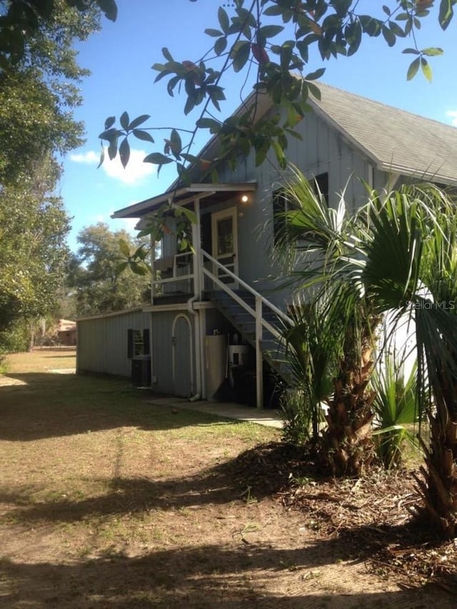 rear view of property featuring stairs and a yard