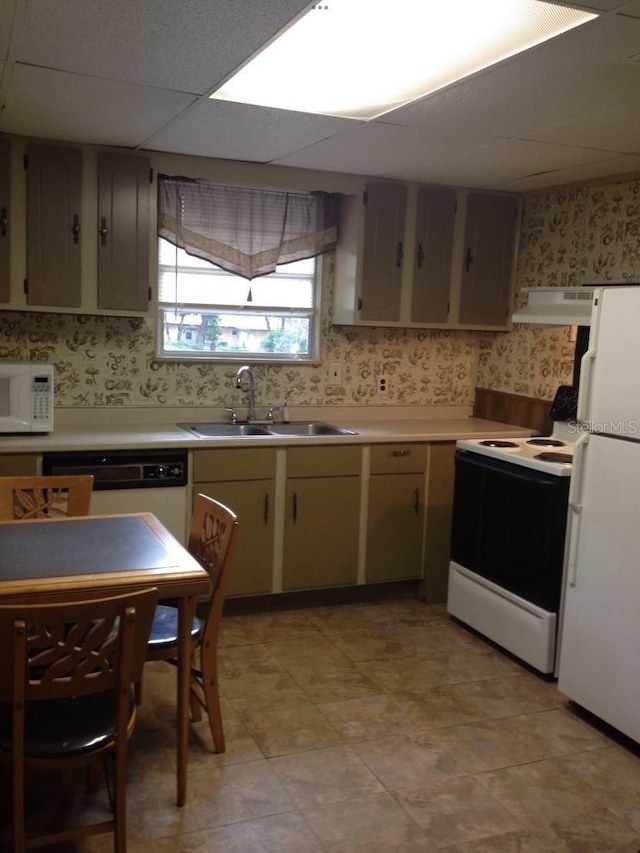kitchen with white appliances, wallpapered walls, under cabinet range hood, a sink, and light countertops