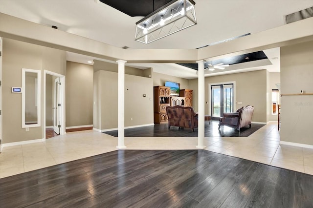 living area with decorative columns, wood finished floors, baseboards, and ceiling fan