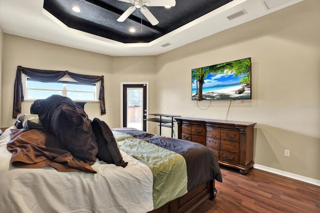 bedroom with a raised ceiling, wood finished floors, baseboards, and ceiling fan