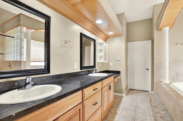 full bath featuring decorative columns, tiled bath, double vanity, and a shower