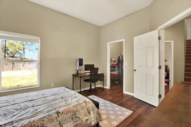 bedroom with a walk in closet, wood finished floors, a closet, and baseboards