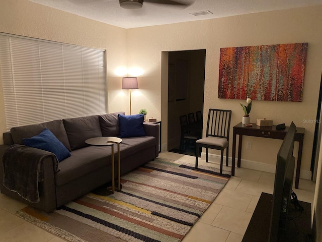 tiled living room featuring a textured wall and ceiling fan