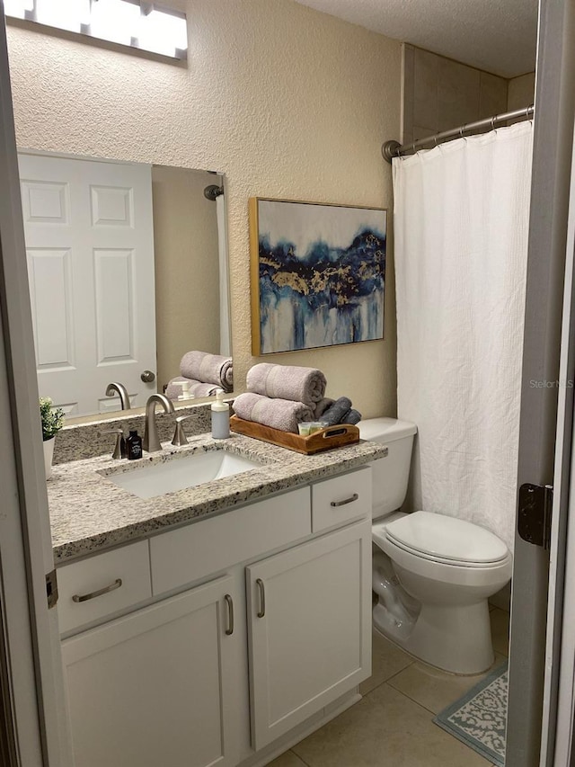 full bathroom featuring a textured wall, tile patterned flooring, vanity, toilet, and curtained shower