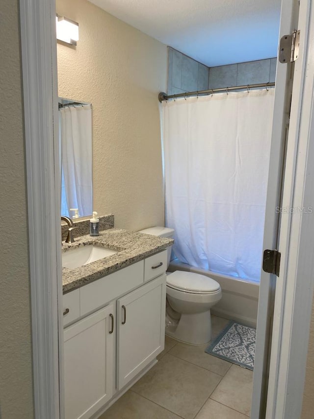full bath featuring a textured wall, tile patterned floors, vanity, toilet, and shower / tub combo with curtain