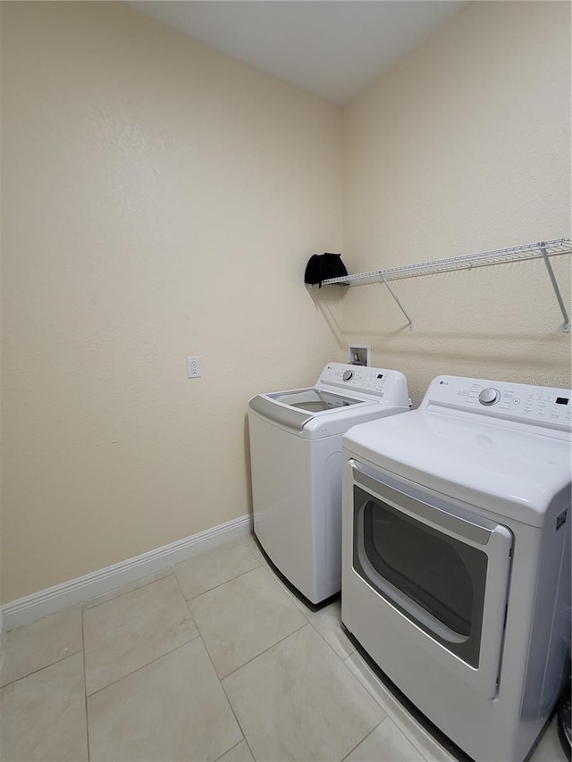 clothes washing area featuring washing machine and clothes dryer, baseboards, and light tile patterned floors