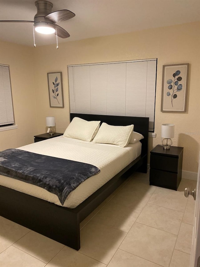 bedroom featuring light tile patterned floors, a ceiling fan, and baseboards