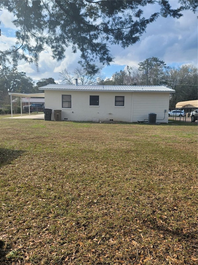 rear view of property featuring metal roof, a yard, central AC unit, and an attached carport