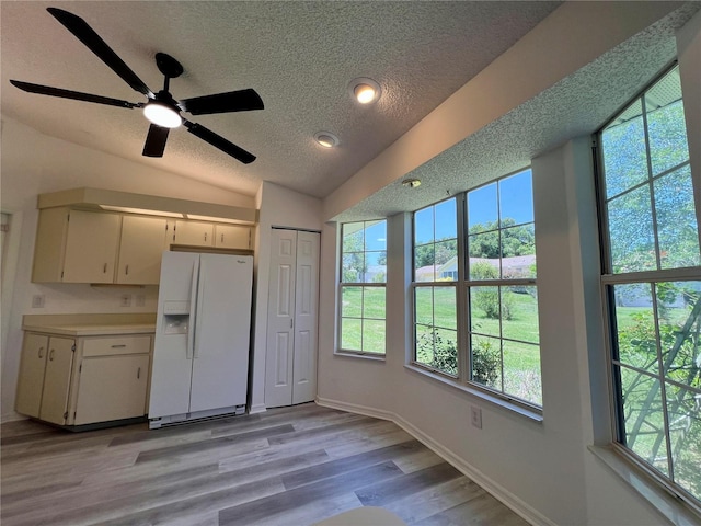 8239 SW 108th St, Ocala, FL 34481 - kitchen featuring white fridge with ice dispenser, a textured ceiling, vaulted ceiling, healthy amount of natural light, and light wood-type flooring