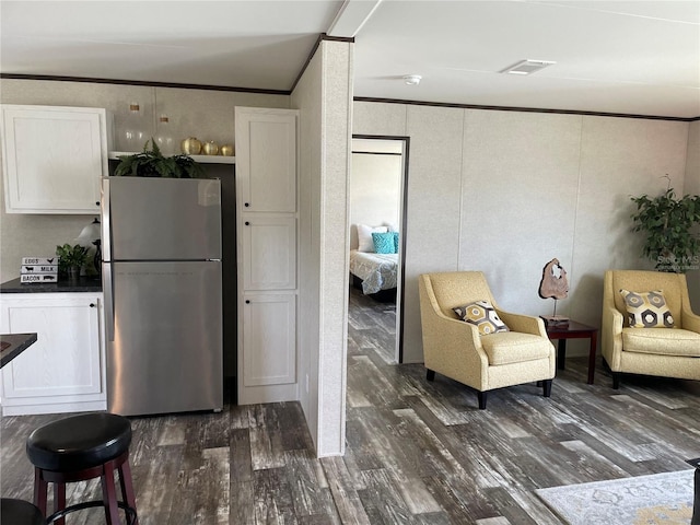 15807 NE 10th St, Williston, FL 32696 - kitchen featuring freestanding refrigerator, dark wood finished floors, white cabinets, ornamental molding, and dark countertops
