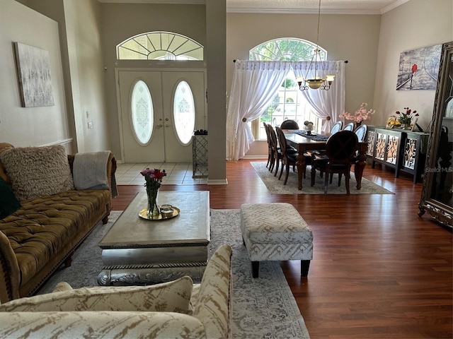 living area with a chandelier, ornamental molding, wood finished floors, and a towering ceiling