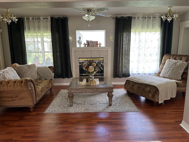 living area featuring a tile fireplace, a ceiling fan, and wood finished floors