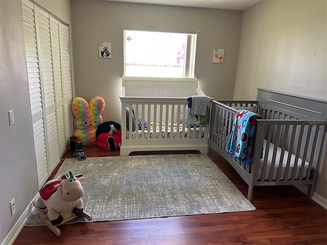 bedroom with wood finished floors, baseboards, and a closet