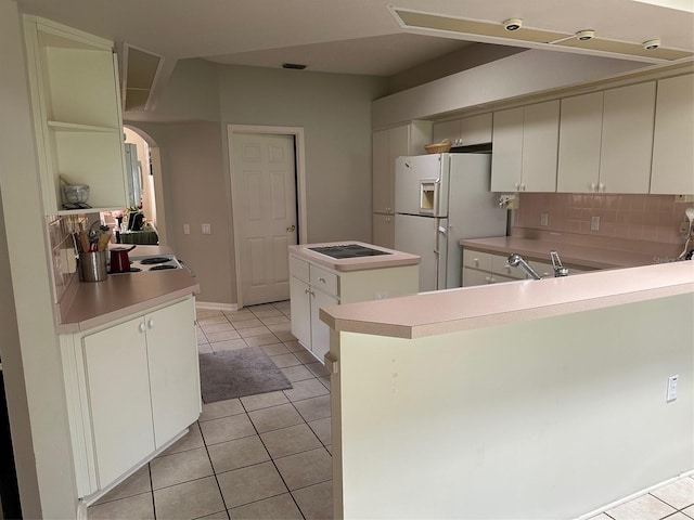 kitchen with freestanding refrigerator, a center island, light tile patterned floors, and arched walkways