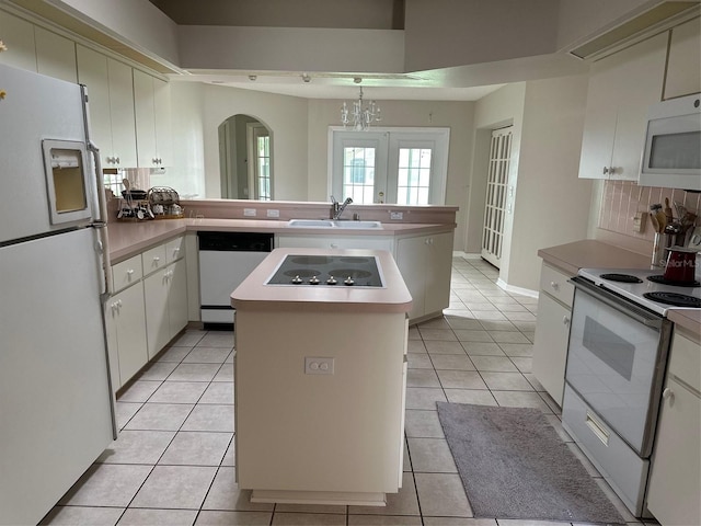 kitchen featuring white appliances, a sink, a peninsula, tasteful backsplash, and light countertops