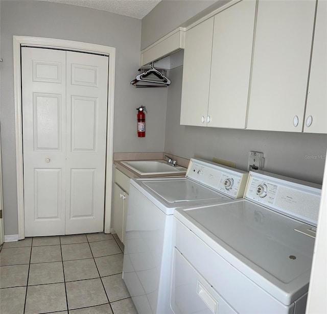 washroom featuring cabinet space, washer and dryer, and light tile patterned floors