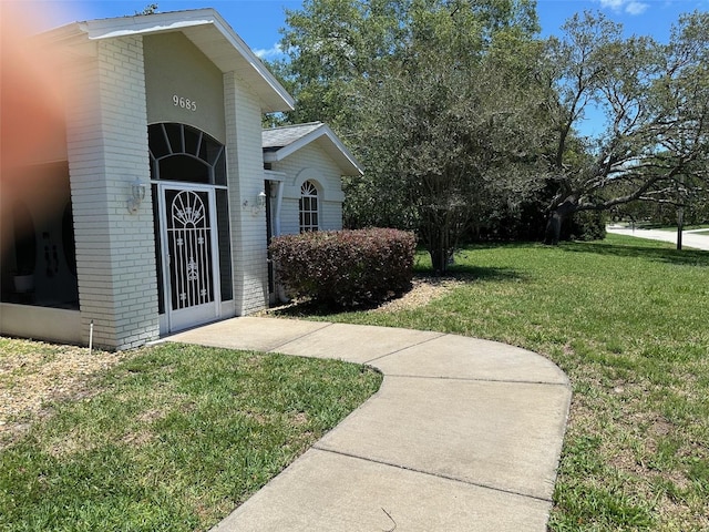 property entrance featuring brick siding and a lawn