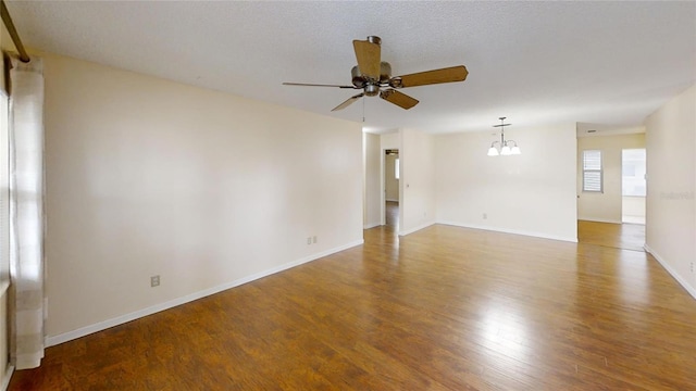 spare room with ceiling fan, wood finished floors, a chandelier, and baseboards