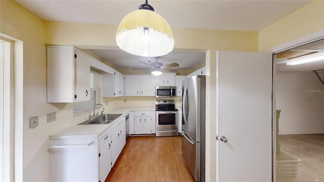 kitchen with stainless steel appliances, a sink, light countertops, white cabinetry, and a ceiling fan