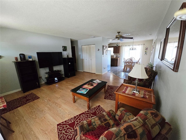 living room featuring a textured ceiling, wood finished floors, a ceiling fan, and baseboards