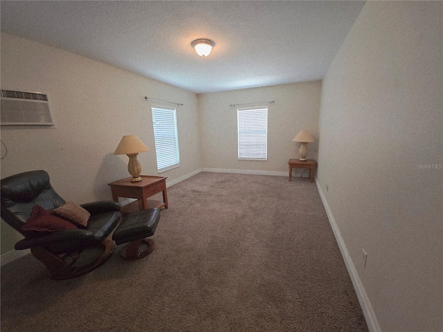 sitting room with a wall mounted air conditioner, carpet, and baseboards