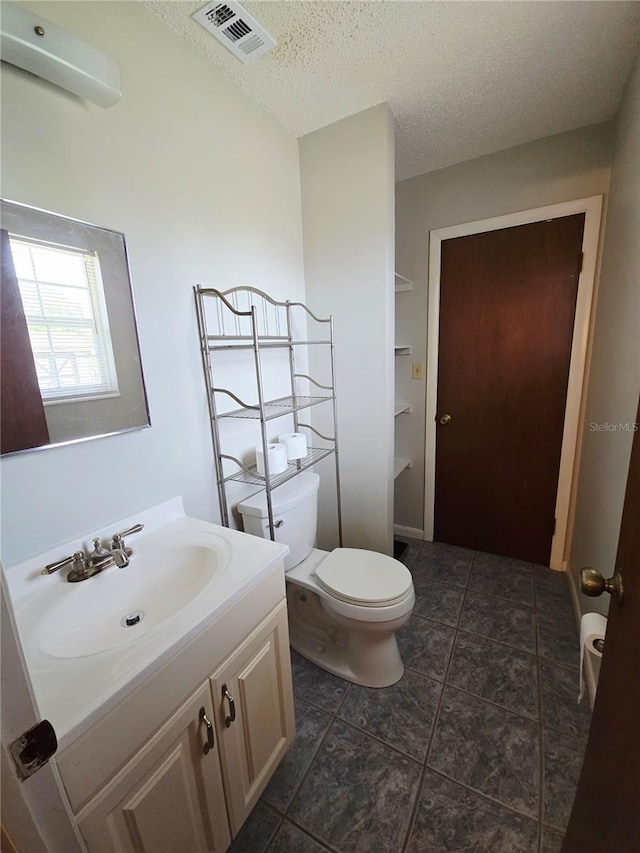 bathroom featuring vanity, toilet, and a textured ceiling