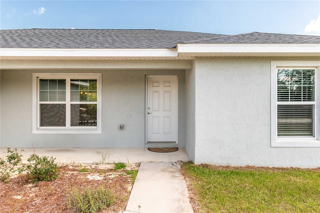 13561 SW 85th Pl, Dunnellon, FL 34432 - view of exterior entry featuring a shingled roof and stucco siding