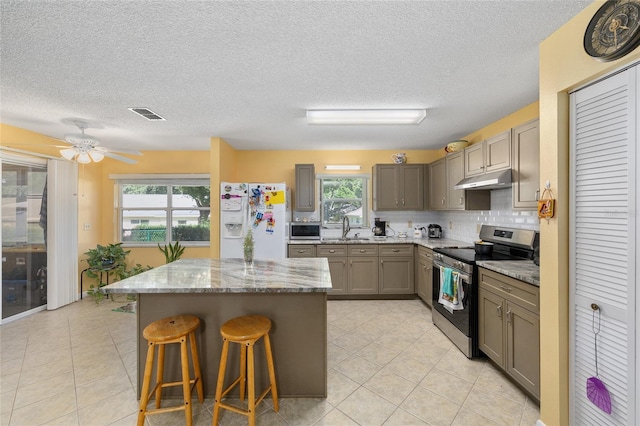 9661 SW 95th Ct Unit B, Ocala, FL 34481 - kitchen featuring appliances with stainless steel finishes, a sink, gray cabinetry, under cabinet range hood, and a kitchen bar