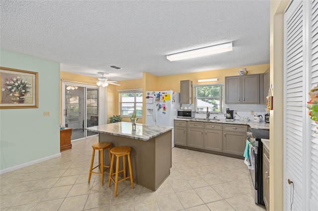 9661 SW 95th Ct Unit B, Ocala, FL 34481 - kitchen with appliances with stainless steel finishes, a kitchen island, gray cabinets, plenty of natural light, and a textured ceiling