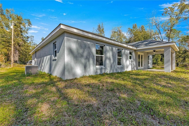 view of property exterior featuring stucco siding, a yard, central AC unit, and ceiling fan