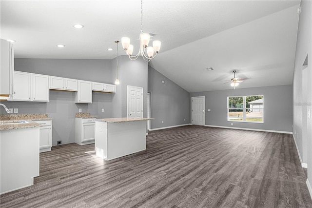 kitchen with a sink, vaulted ceiling, dark wood-style flooring, a kitchen island, and white cabinetry