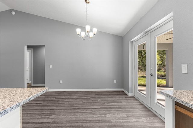 unfurnished dining area with lofted ceiling, a chandelier, dark wood-type flooring, and baseboards