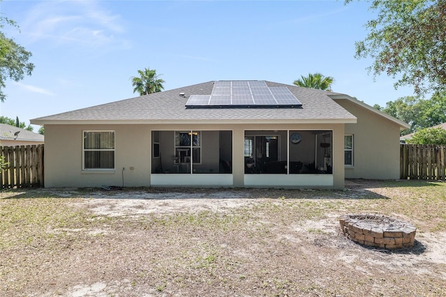 8053 SW 62nd Ave, Ocala, FL 34476 - back of house featuring a sunroom, a fire pit, solar panels, fence, and a shingled roof