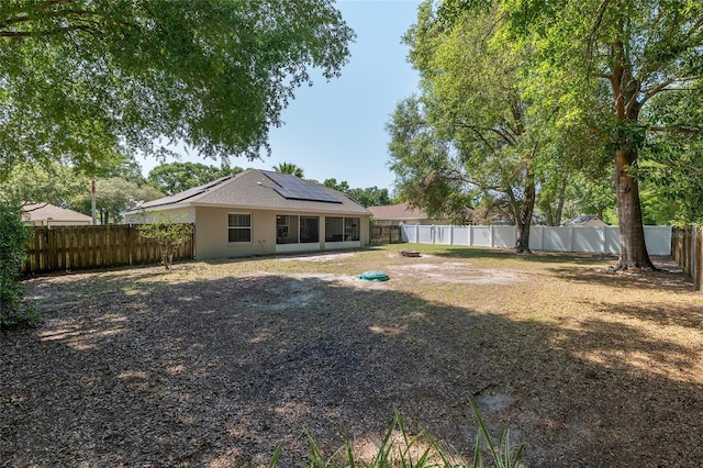 8053 SW 62nd Ave, Ocala, FL 34476 - rear view of house featuring solar panels, a fenced backyard, and stucco siding