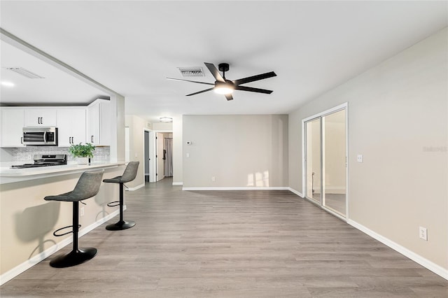 9729 SW 97th St, Ocala, FL 34481 - kitchen featuring appliances with stainless steel finishes, a breakfast bar area, a ceiling fan, and light wood-style floors