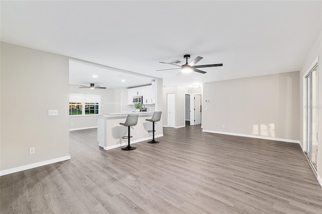 9729 SW 97th St, Ocala, FL 34481 - unfurnished living room featuring a ceiling fan, light wood-style floors, and baseboards