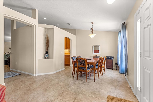 dining space with arched walkways, baseboards, recessed lighting, light tile patterned floors, and a textured ceiling