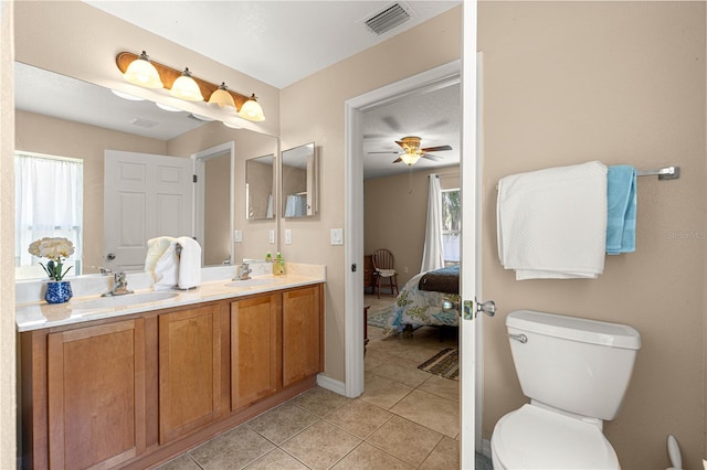 bathroom with tile patterned floors, toilet, a ceiling fan, double vanity, and ensuite bathroom
