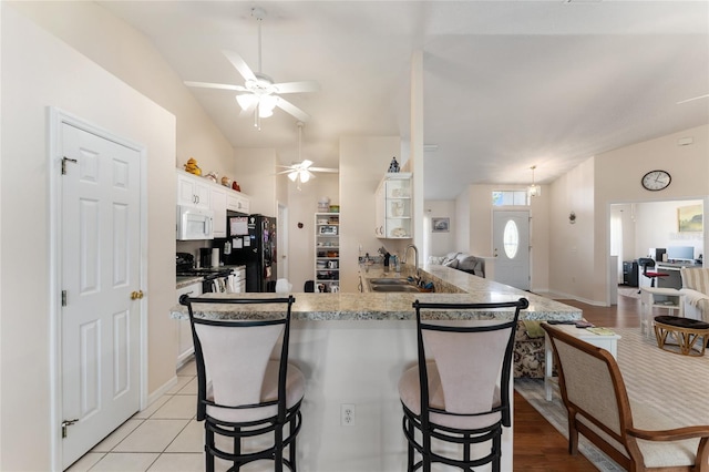 5920 SW 88th Pl, Ocala, FL 34476 - kitchen with white microwave, a sink, a ceiling fan, freestanding refrigerator, and a breakfast bar area