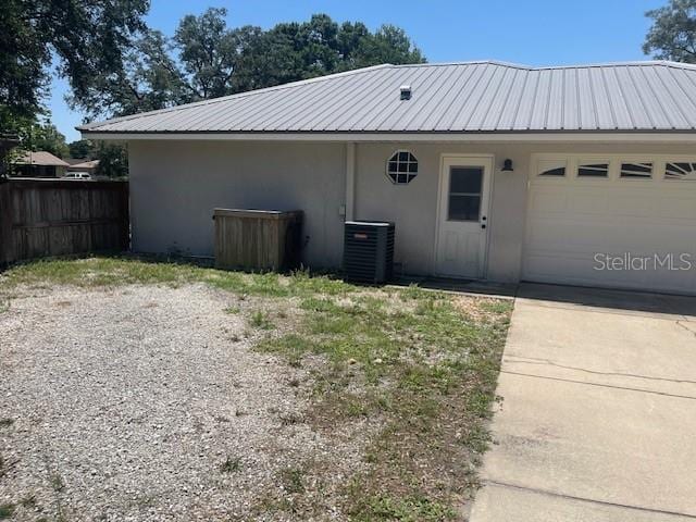 6051 NE 25th Ave, Ocala, FL 34479 - view of home's exterior with stucco siding, fence, a garage, metal roof, and cooling unit