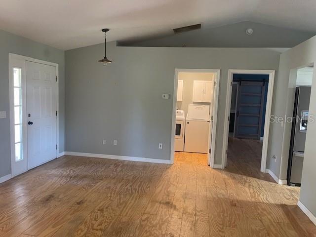 6051 NE 25th Ave, Ocala, FL 34479 - entrance foyer featuring wood finished floors, lofted ceiling, baseboards, and washer and clothes dryer