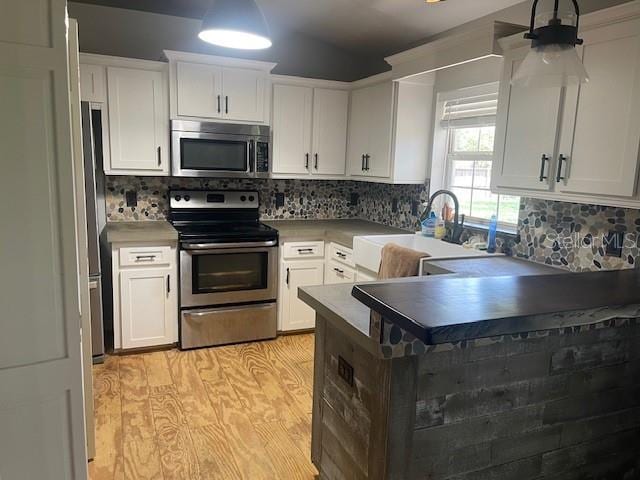 6051 NE 25th Ave, Ocala, FL 34479 - kitchen featuring stainless steel appliances, a sink, white cabinetry, light wood-type flooring, and decorative backsplash