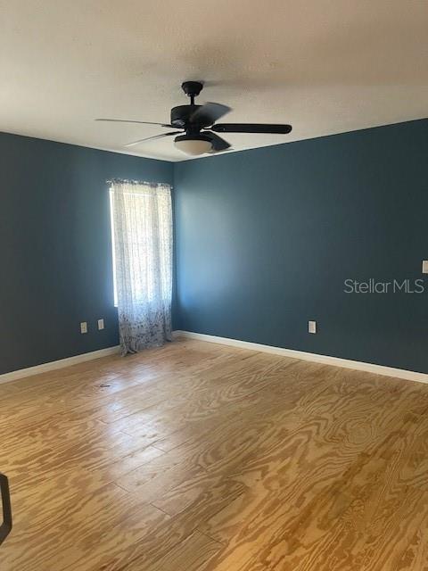 6051 NE 25th Ave, Ocala, FL 34479 - unfurnished room with a ceiling fan, wood finished floors, and baseboards